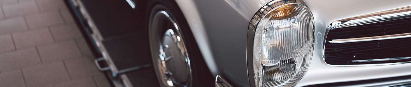 Detailaufnahme eines klassischen silberfarbenem Oldtimers – verchromter Scheinwerfer und Kühlergrill, Symbol für professionelle Oldtimerbewertung bei der GTÜ